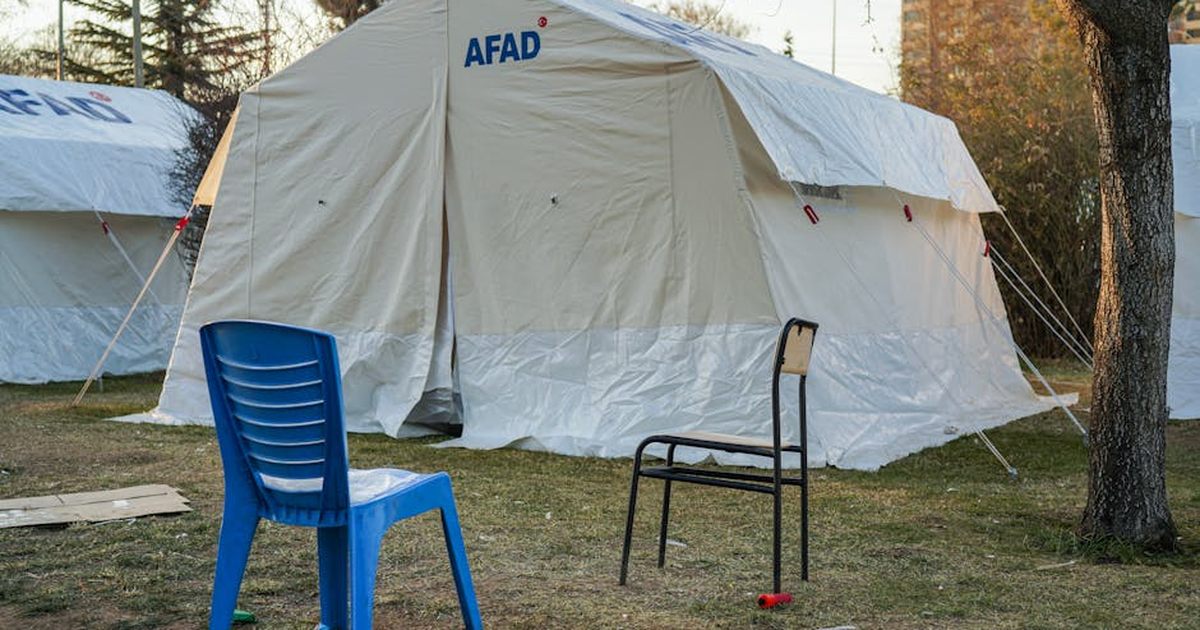 Emergency tents set up in Gaziantep for disaster relief efforts, featuring chairs and trees.
