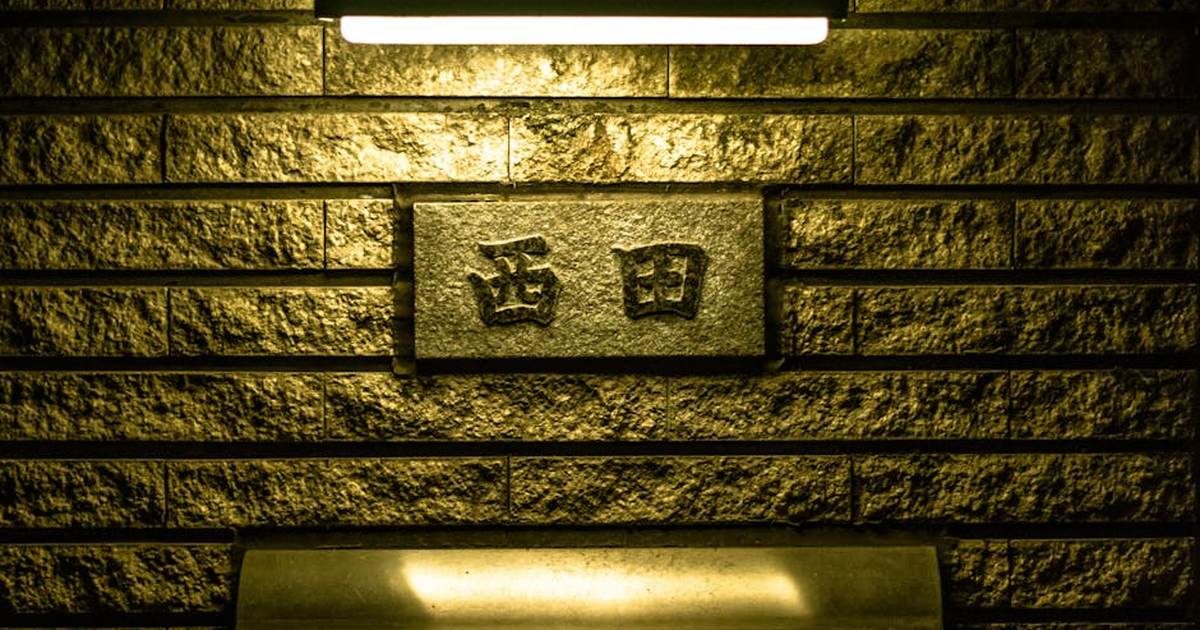 A plaque with Japanese characters on a lit brick wall, creating a moody atmosphere.
