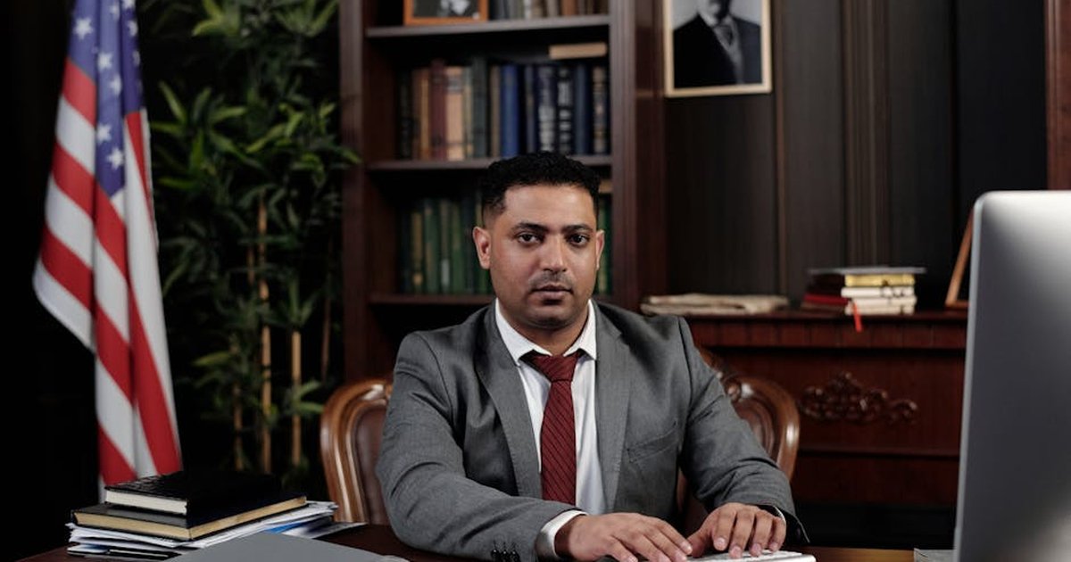 Corporate professional sitting at desk with American flag in office.