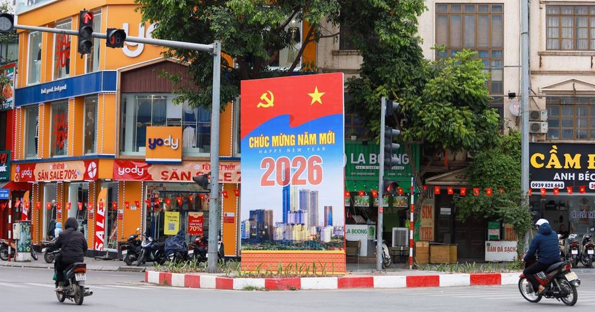 Vibrant Hà Nội street scene featuring a New Year 2026 billboard, motorcycles, and colorful shops.
