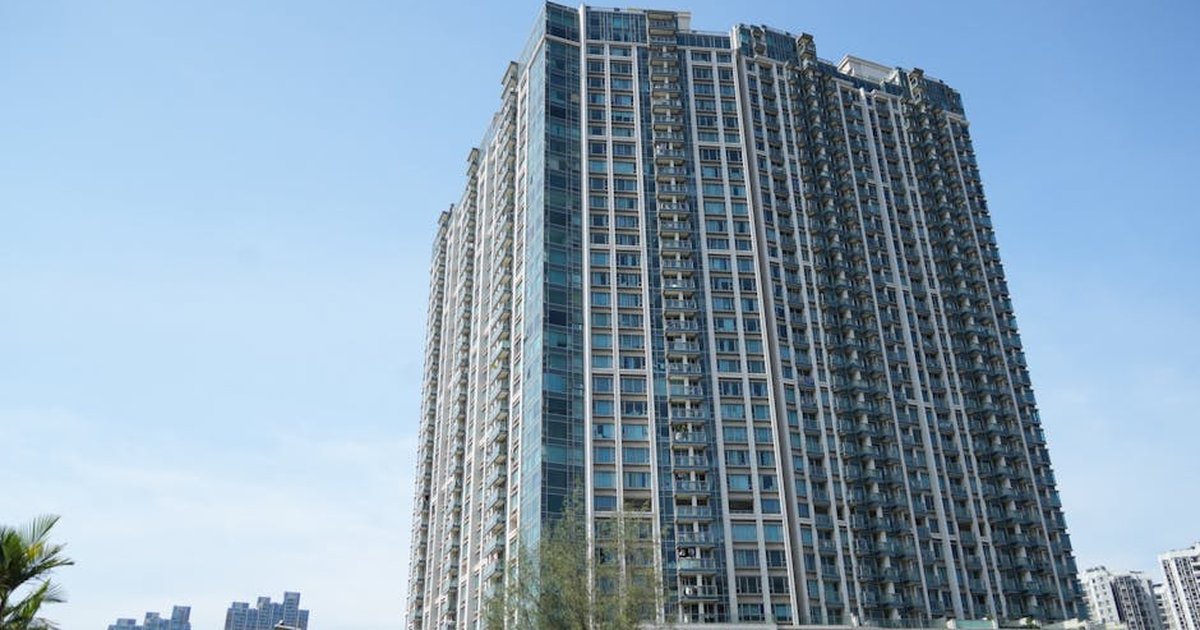 Tall residential skyscraper in Hong Kong against a clear blue sky, showcasing modern architecture.