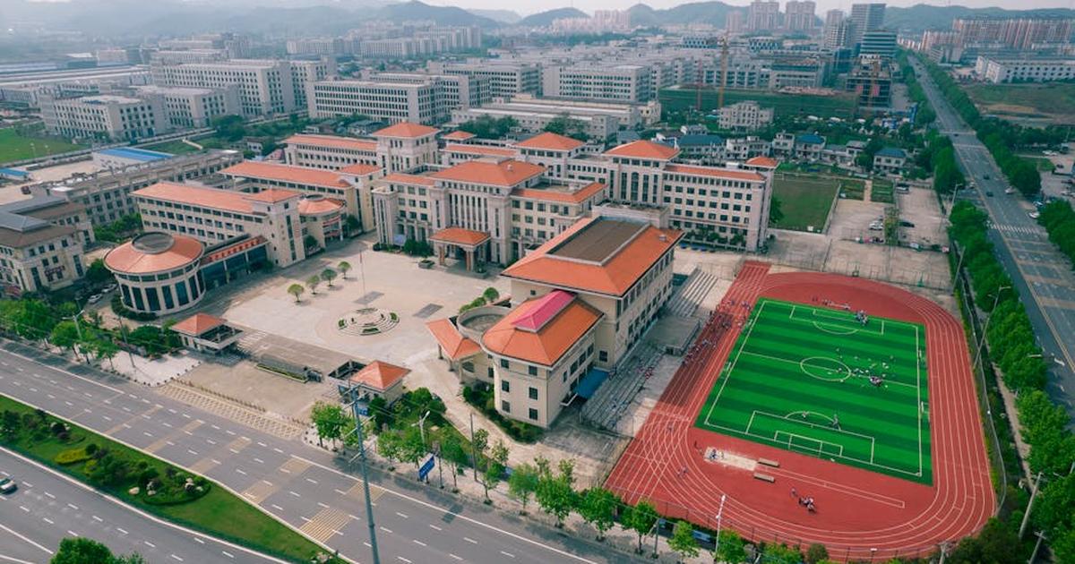 Aerial view of a modern school campus with sports field in Jiujiang, China.