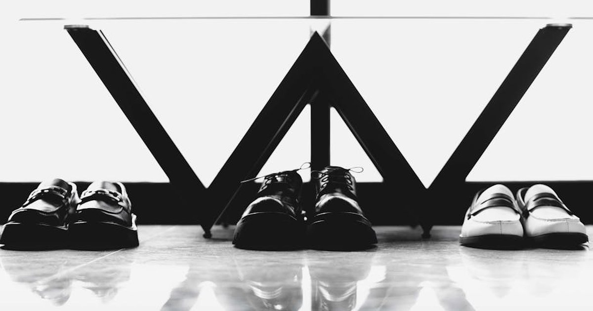 Black and white photo of formal shoes arranged under a modern table, emphasizing style and order.