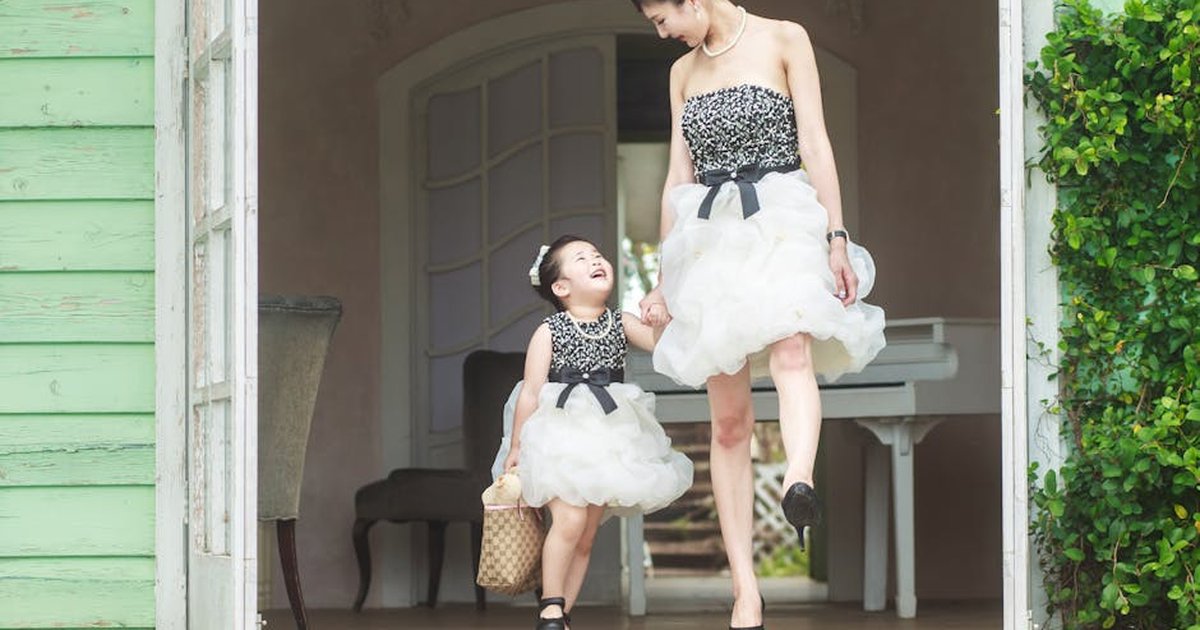 Elegant mother and daughter in matching dresses enjoying a sunny day outside.