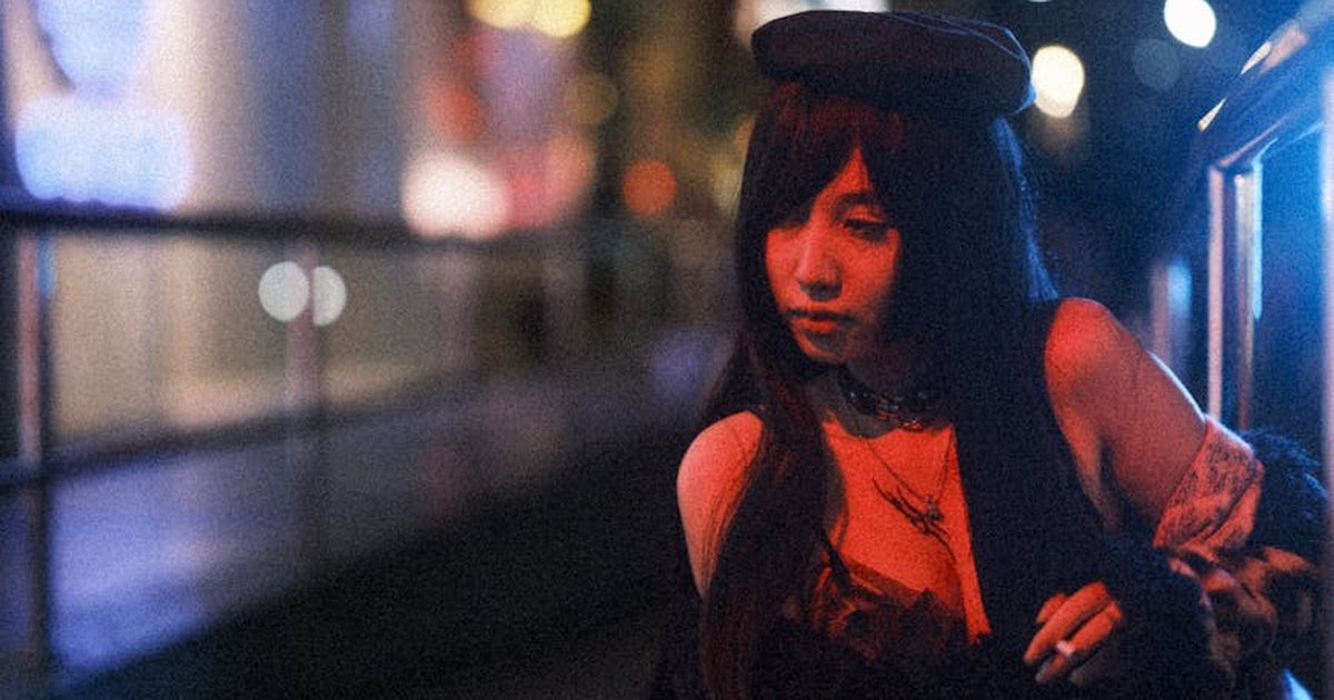 A stylish woman in urban setting illuminated by vibrant neon lights at night.