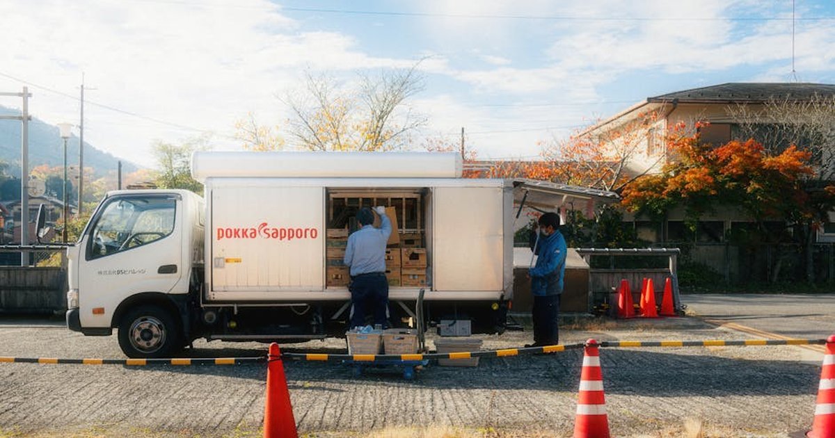 A delivery truck being unloaded in a Japanese suburb during autumn.