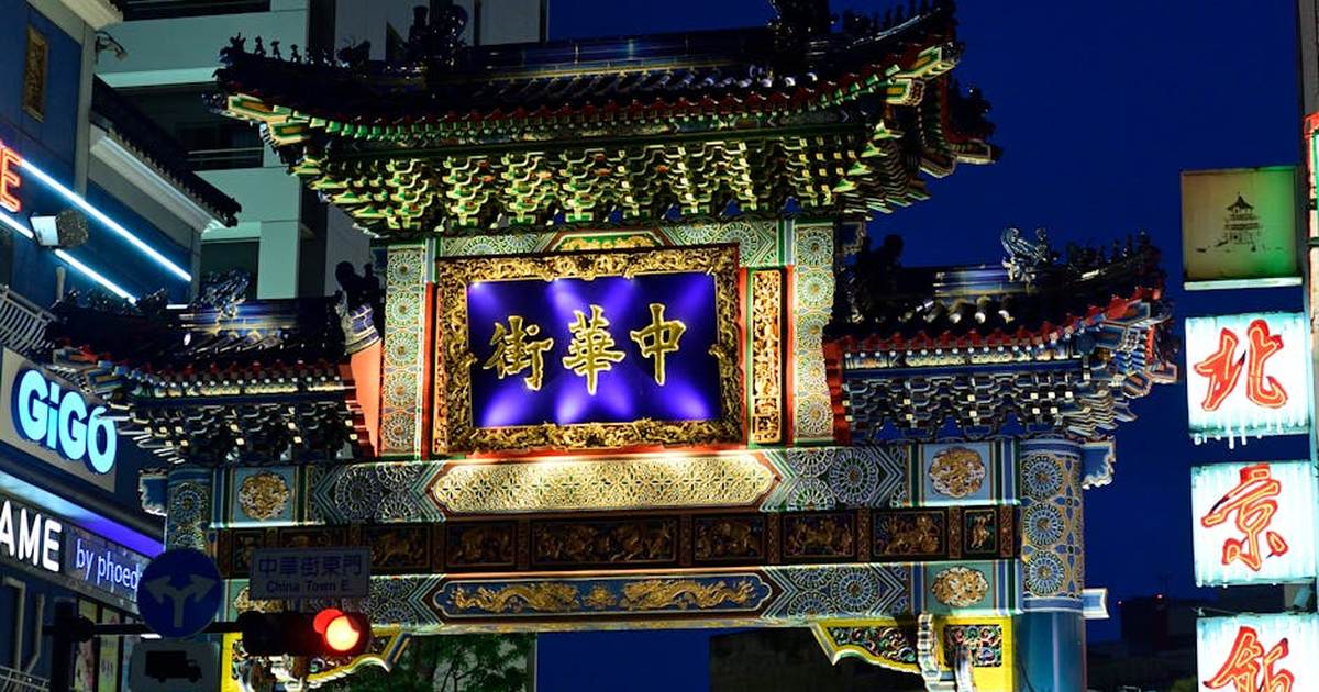 Illuminated Chinatown gate in Yokohama, Japan, showcasing traditional Asian architecture at dusk.