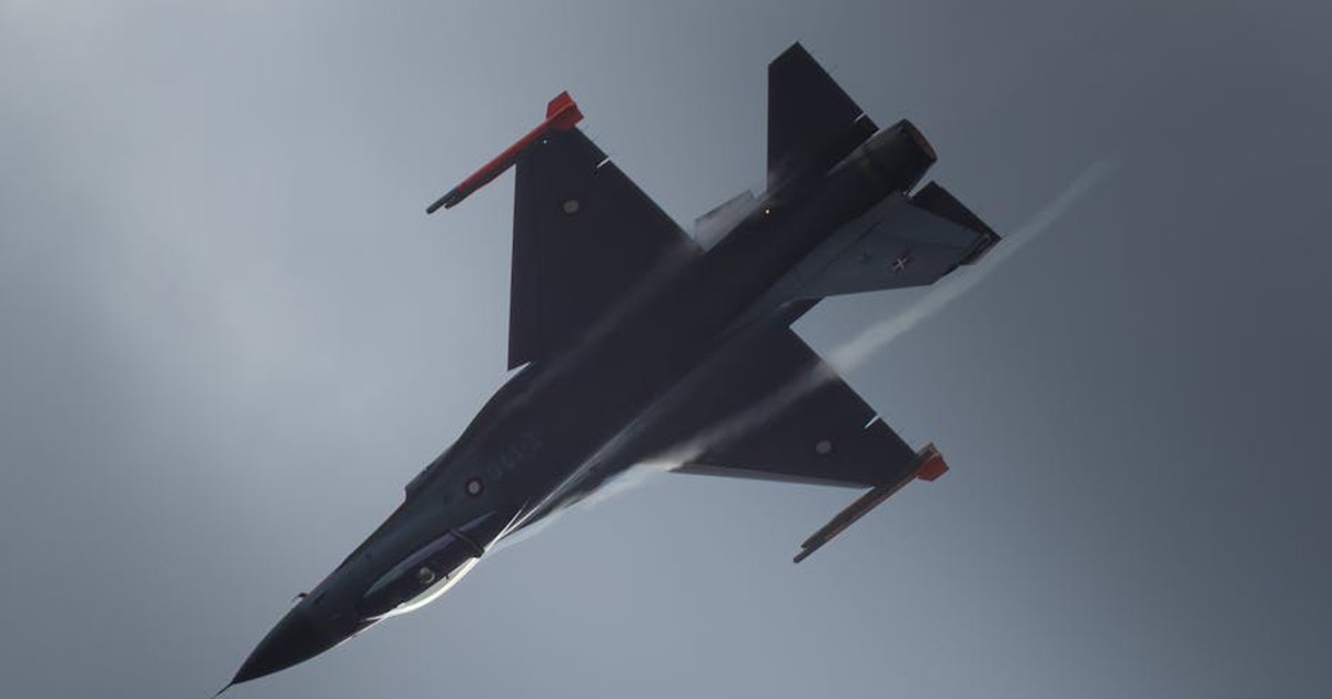 A jet aircraft performs an aerial maneuver against a moody overcast sky.