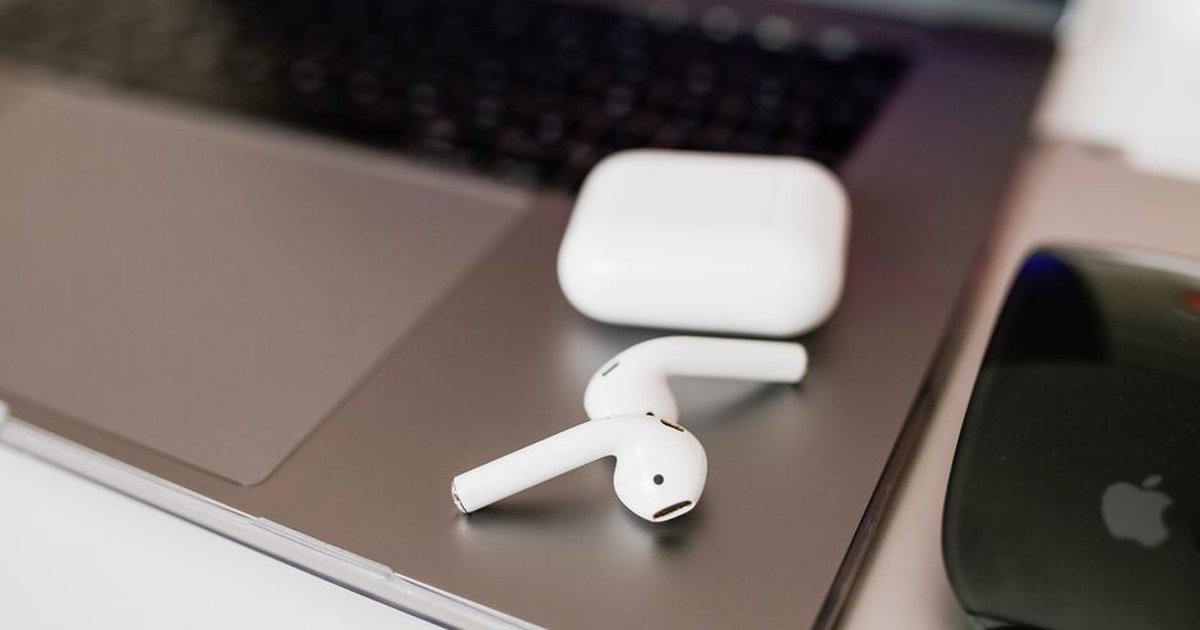 White wireless earbuds and charging case on a sleek laptop close-up.