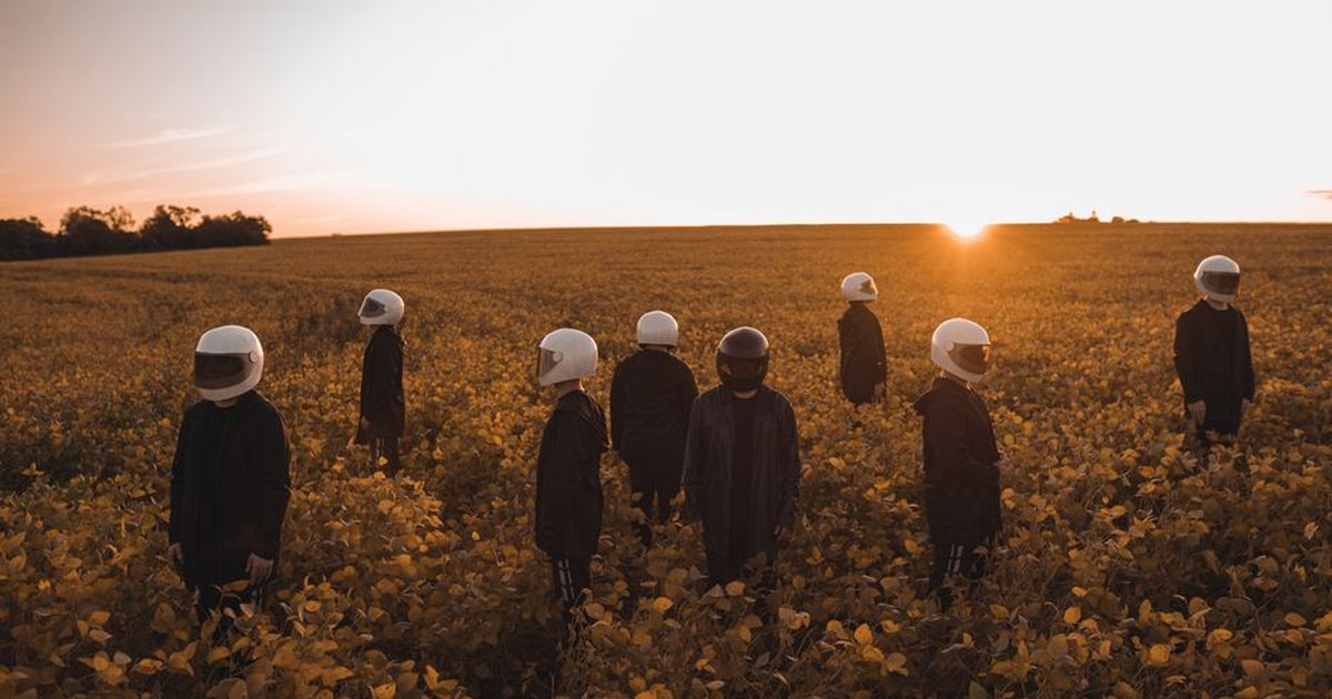 Group of people in helmets standing in a vibrant yellow field at sunset.