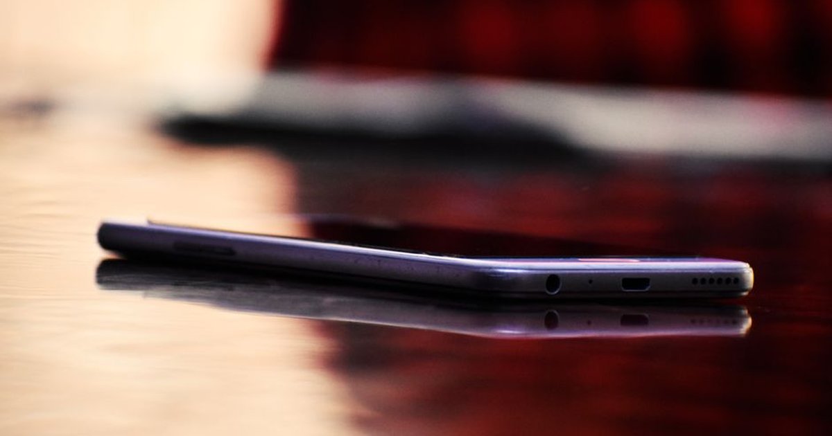 Close-up of a smartphone reflected on a shiny wooden table indoors.