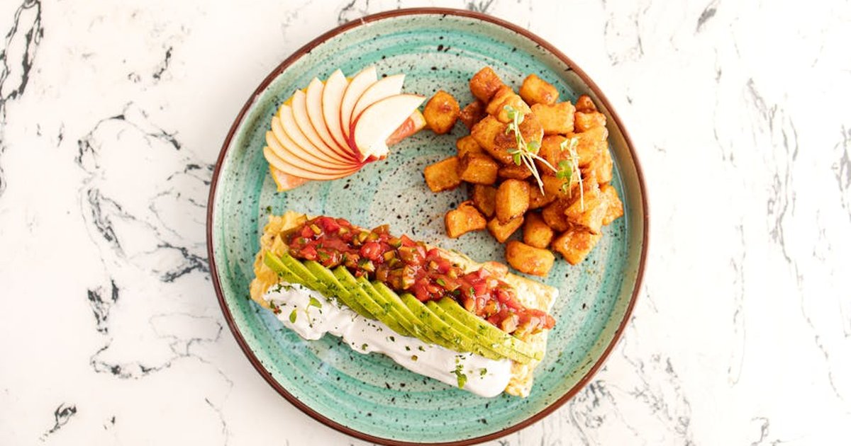 Delicious avocado toast with apples and crispy potatoes on a turquoise plate.