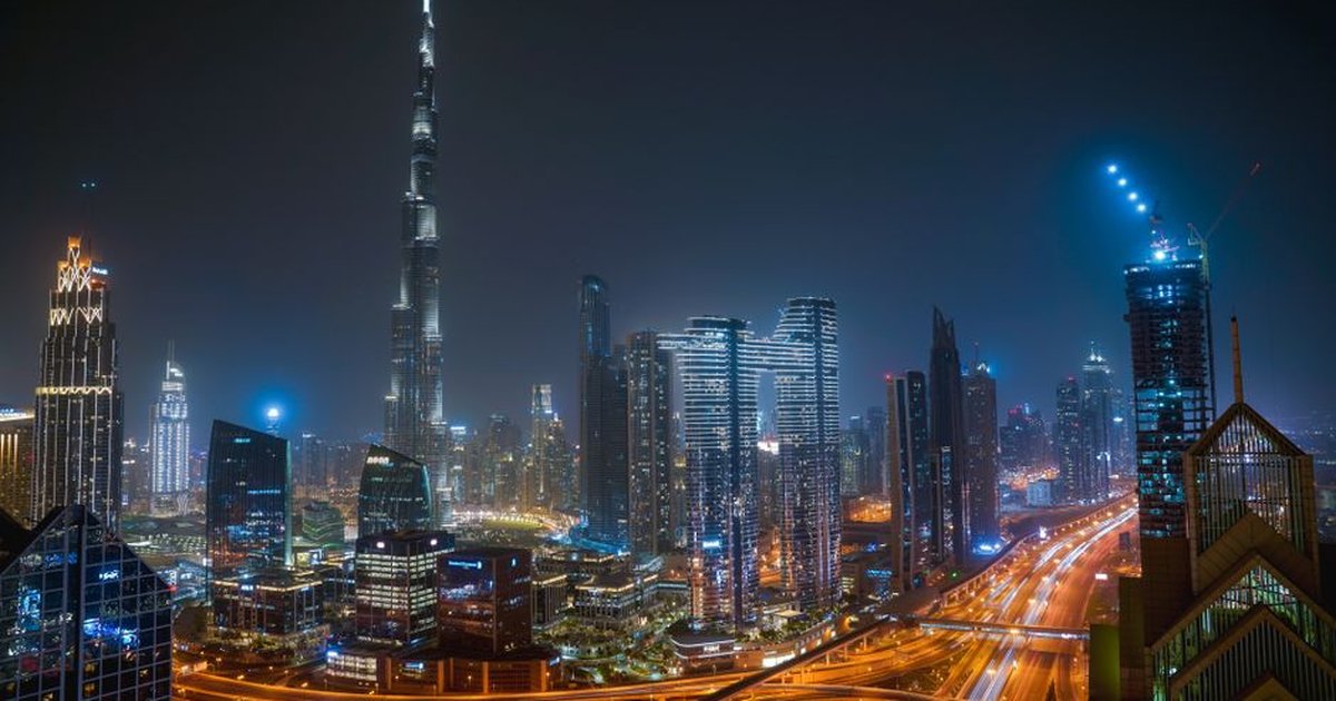 Beautiful night view of Dubai city skyline with Burj Khalifa towering over illuminated roads and skyscrapers.