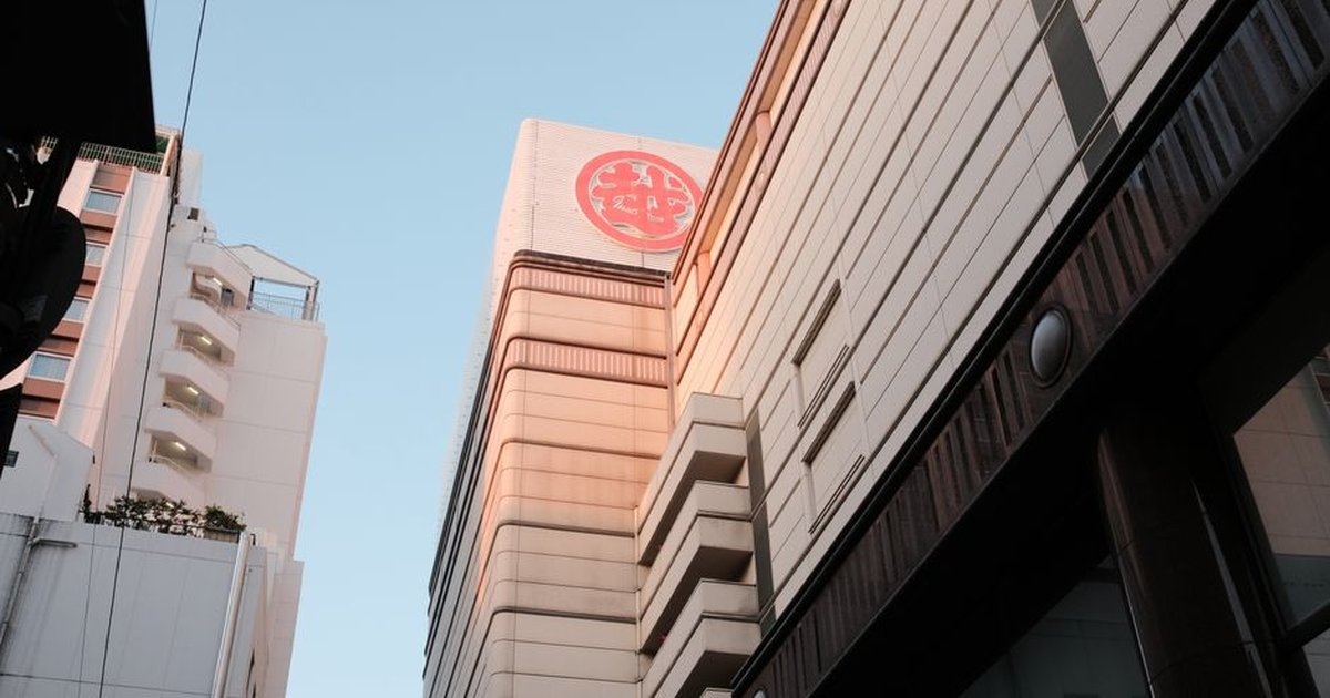 View of a modern skyscraper in an urban setting with prominent Japanese signage.