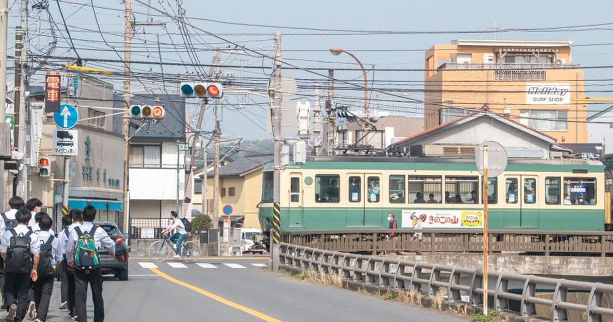 A vibrant urban street scene in Japan with a train and pedestrians.