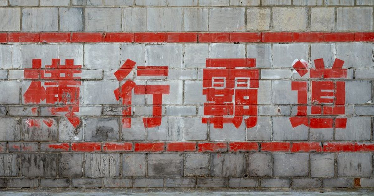 Chinese characters painted in red on an aged stone wall in Luoyang, China.