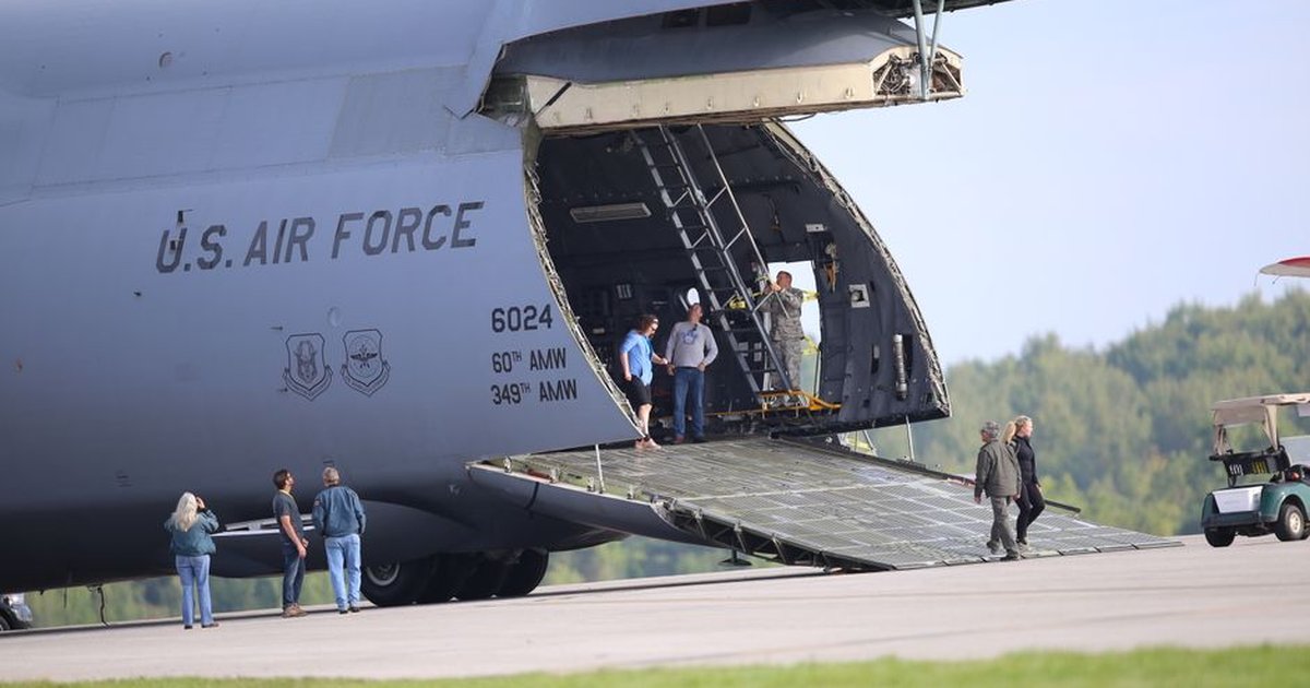 U.S. Air Force cargo plane with open ramp and personnel preparing for loading at the airfield.