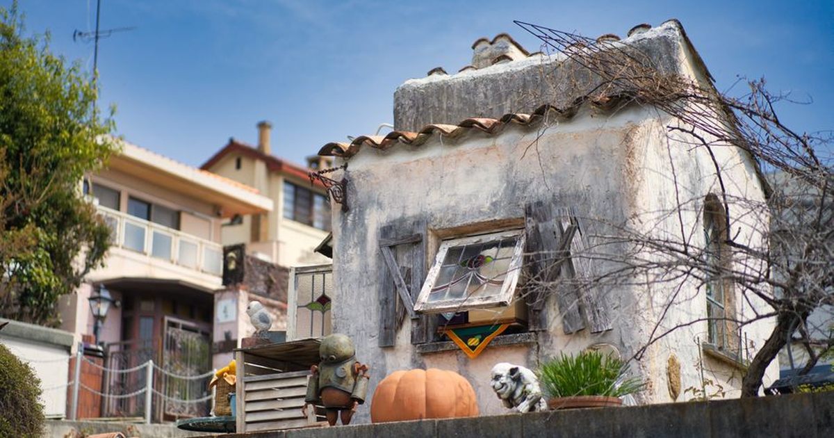 Whimsical miniature house display with rustic details, located outdoors in sunny Kobe, Japan.