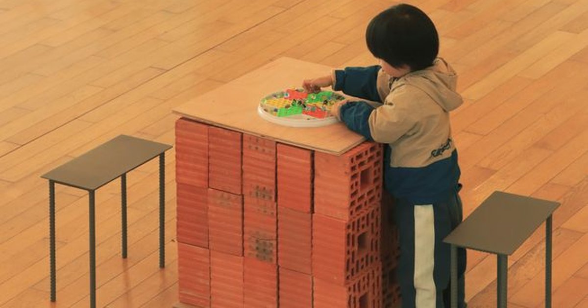 Young child playing with a toy on a brick palette indoors, creating a scene of creativity and imagination.