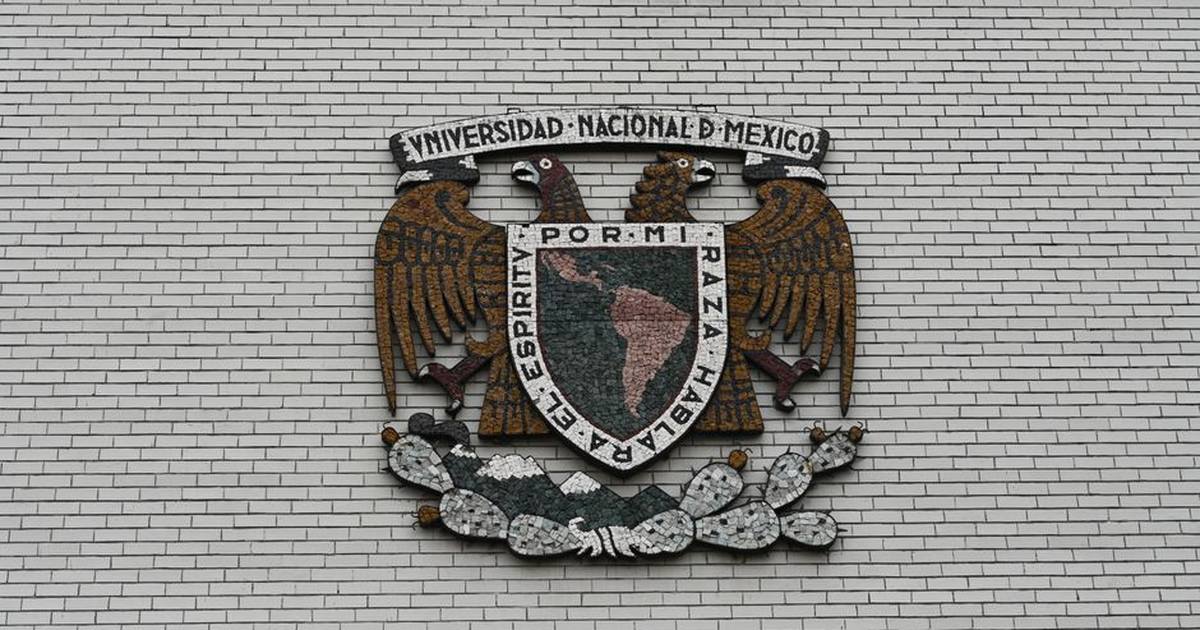 Close-up of the Universidad Nacional de Mexico crest on a white brick wall.