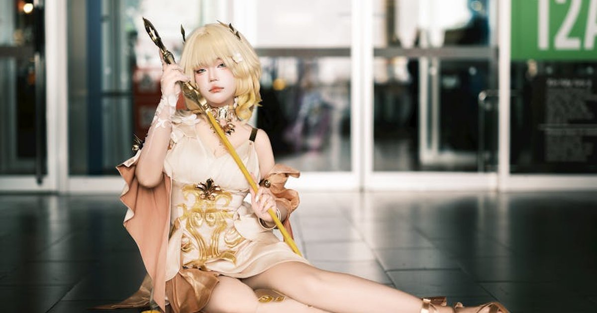 Cosplayer in an elegant fantasy costume sitting indoors, embracing fantasy themes.