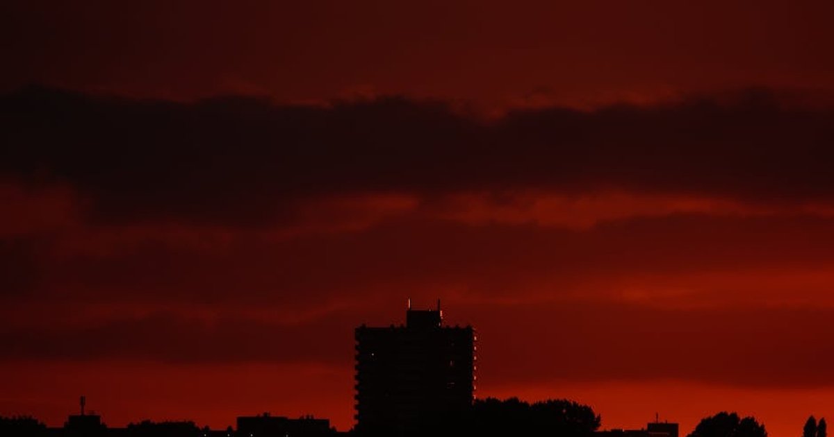 Silhouette of buildings under a red sky during twilight, creating a dramatic urban landscape.