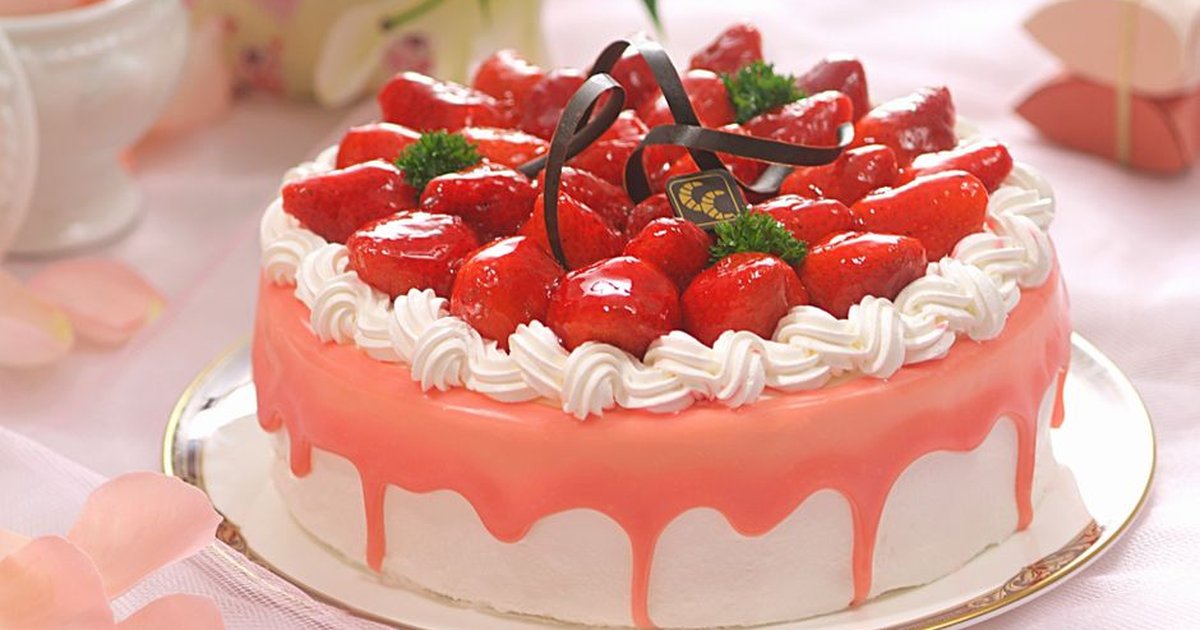 Scrumptious strawberry cake topped with glazed strawberries and whipped cream for your dessert table.