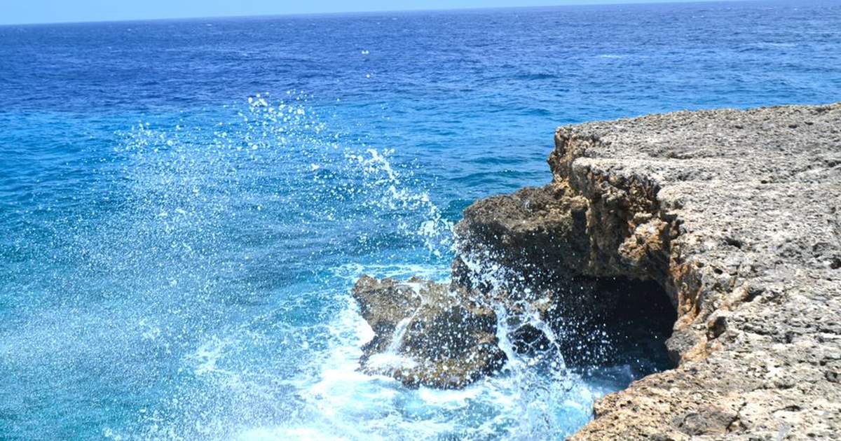 Vibrant ocean waves splashing against the rocky shoreline of Curaçao. A perfect tropical seascape for travel inspiration.