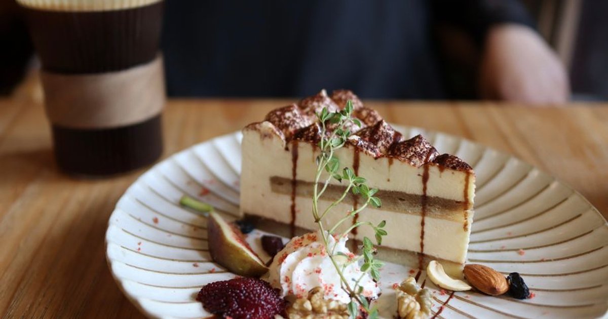 Close-up of tiramisu with nuts and coffee on a wooden table, creating a delicious culinary setting.