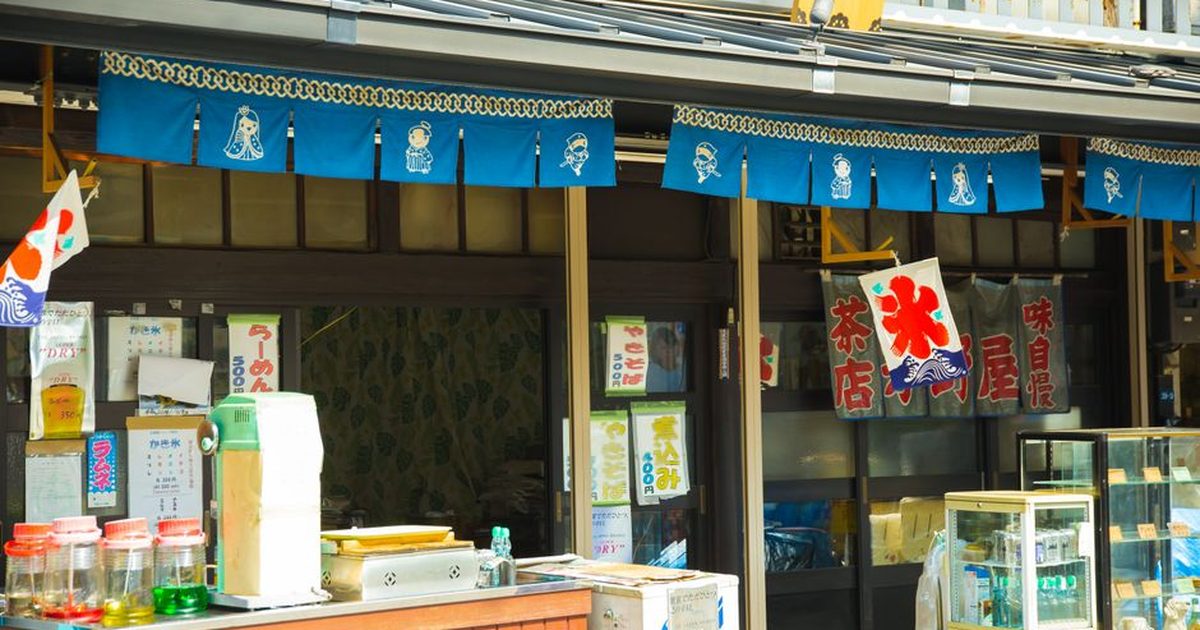 Street trade shops with drinks for sale near building with bright hieroglyphs in oriental town