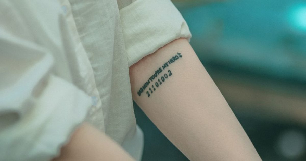 A detailed view of a tattoo on an arm with black text on a blurred backdrop.
