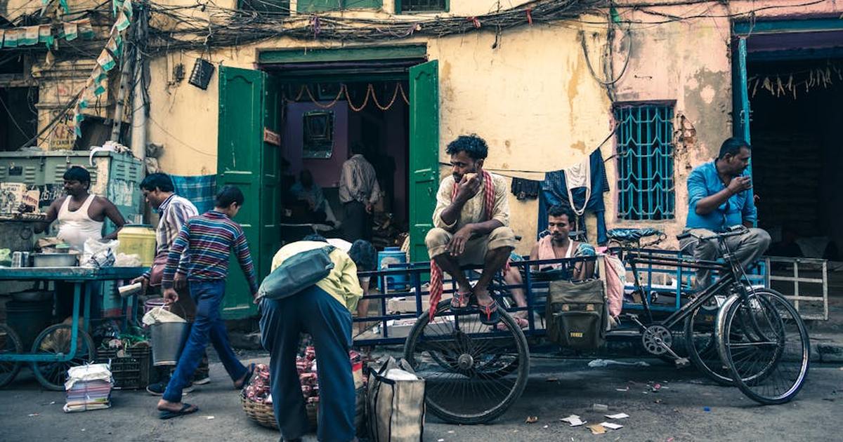 Lively street scene in Kolkata featuring men with freight tricycles, vendors, and urban life.