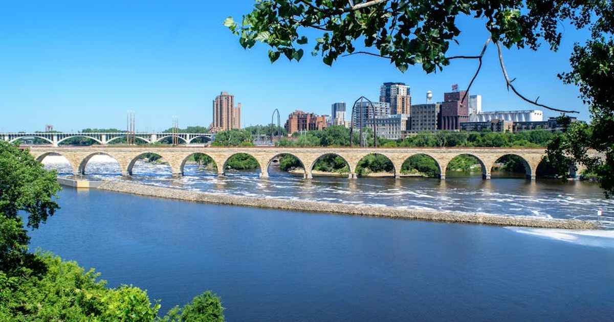 A stunning view of the Stone Arch Bridge and Mississippi River in Minneapolis on a clear summer day.