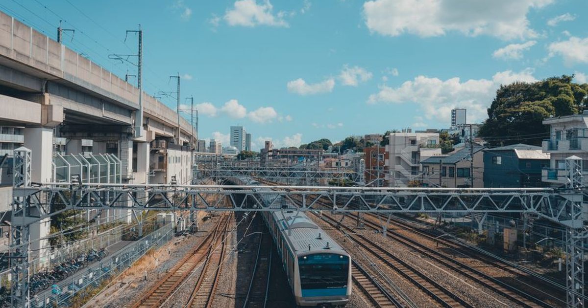 A train traversing elevated tracks in Tokyo's urban landscape, showcasing modern infrastructure.