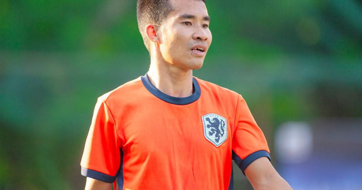 Male football player wearing an orange jersey during a game in Hà Nội.