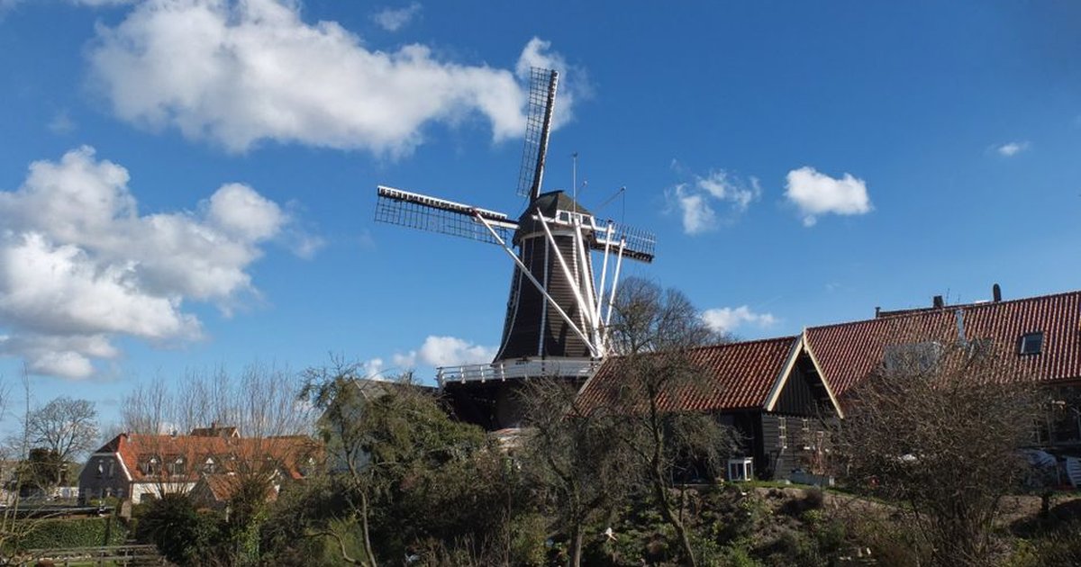 A scenic view of a traditional windmill in Hattem, Gelderland on a sunny day.