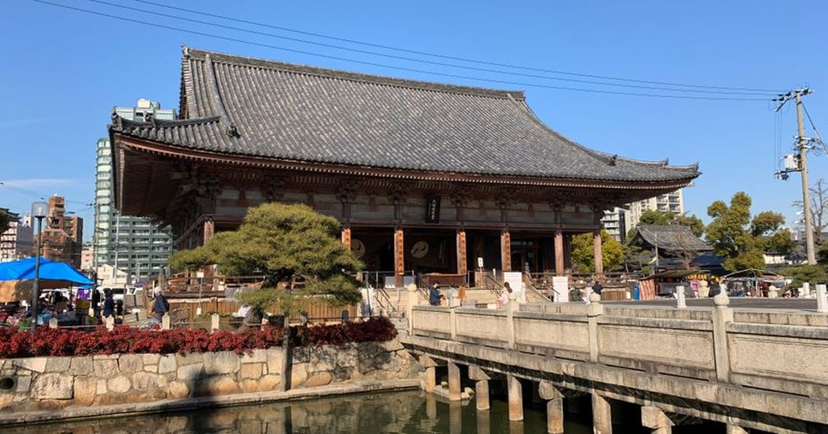 Explore the historic Shitennoji Temple in Osaka, Japan, with its traditional architecture and serene reflection on a sunny day.