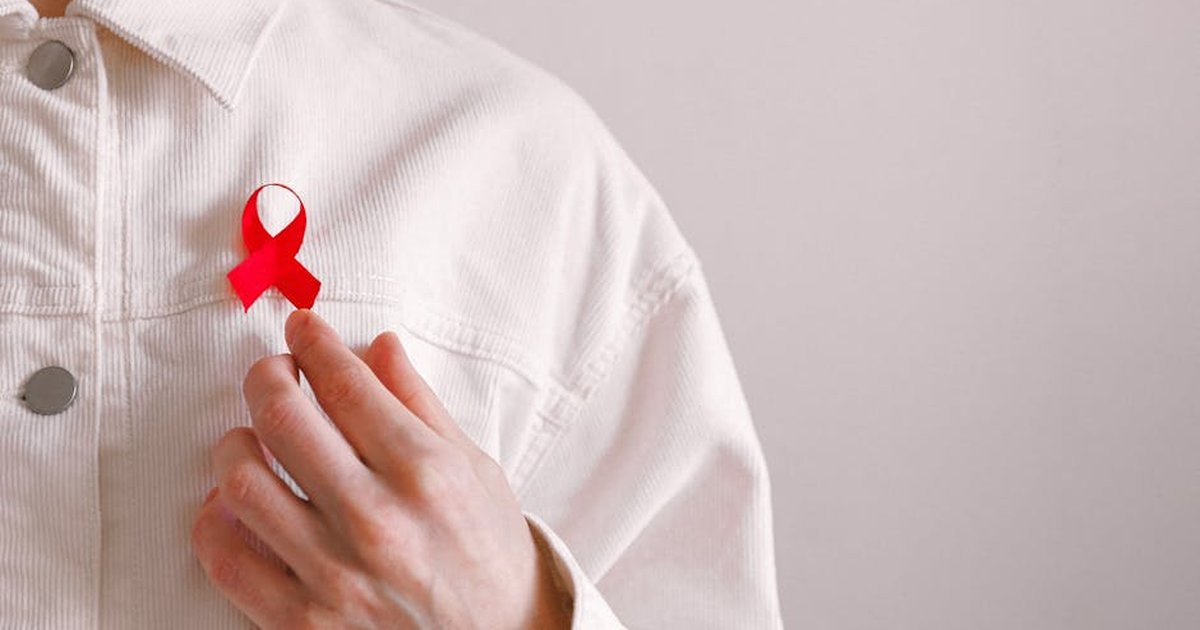 Close-up of a red ribbon on a white shirt symbolizing AIDS awareness and support.