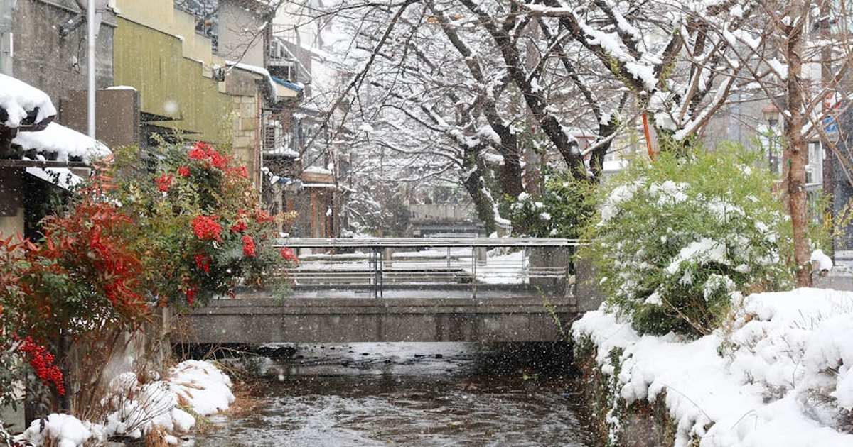 Charming winter view of a snowy canal and bridge in Kyoto, Japan.