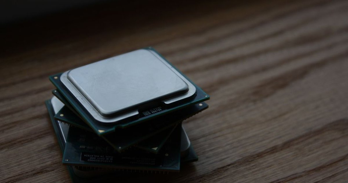 Close-up of multiple computer CPUs stacked on a wooden surface, showcasing technology components.