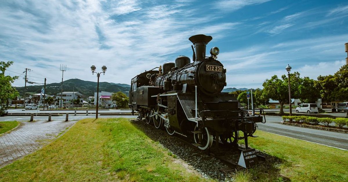 Historic steam locomotive showcased outdoors under a clear sky in a park setting.
