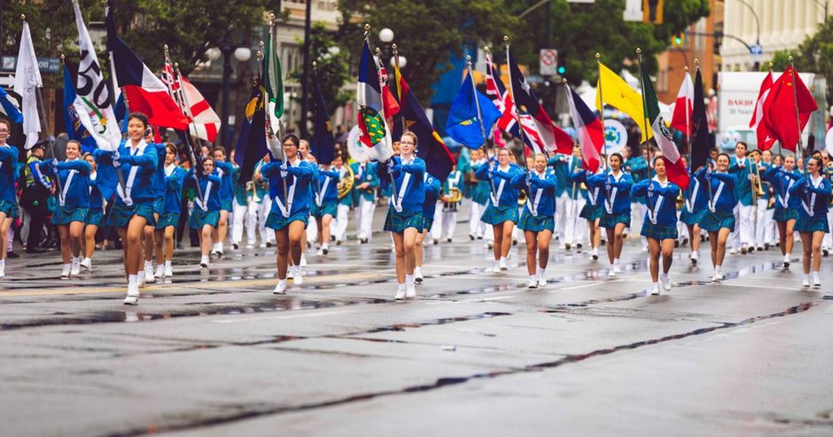 A vibrant marching band parades through the streets of Victoria, BC, showcasing flags and uniforms.