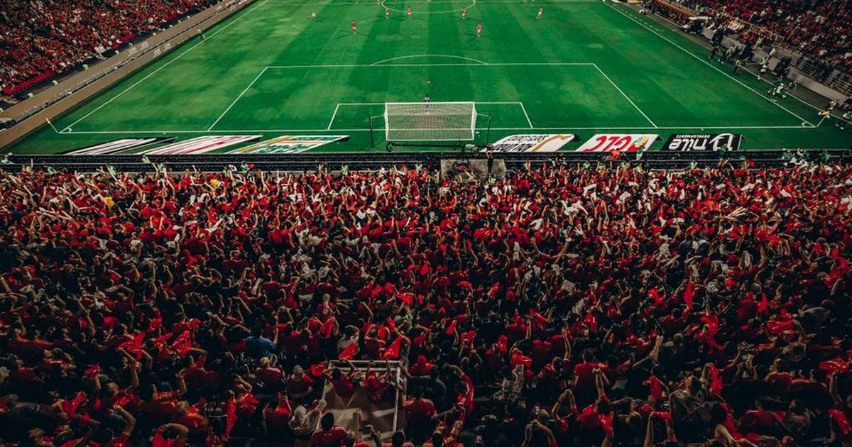 Aerial shot of a lively football match with enthusiastic fans in a packed stadium.