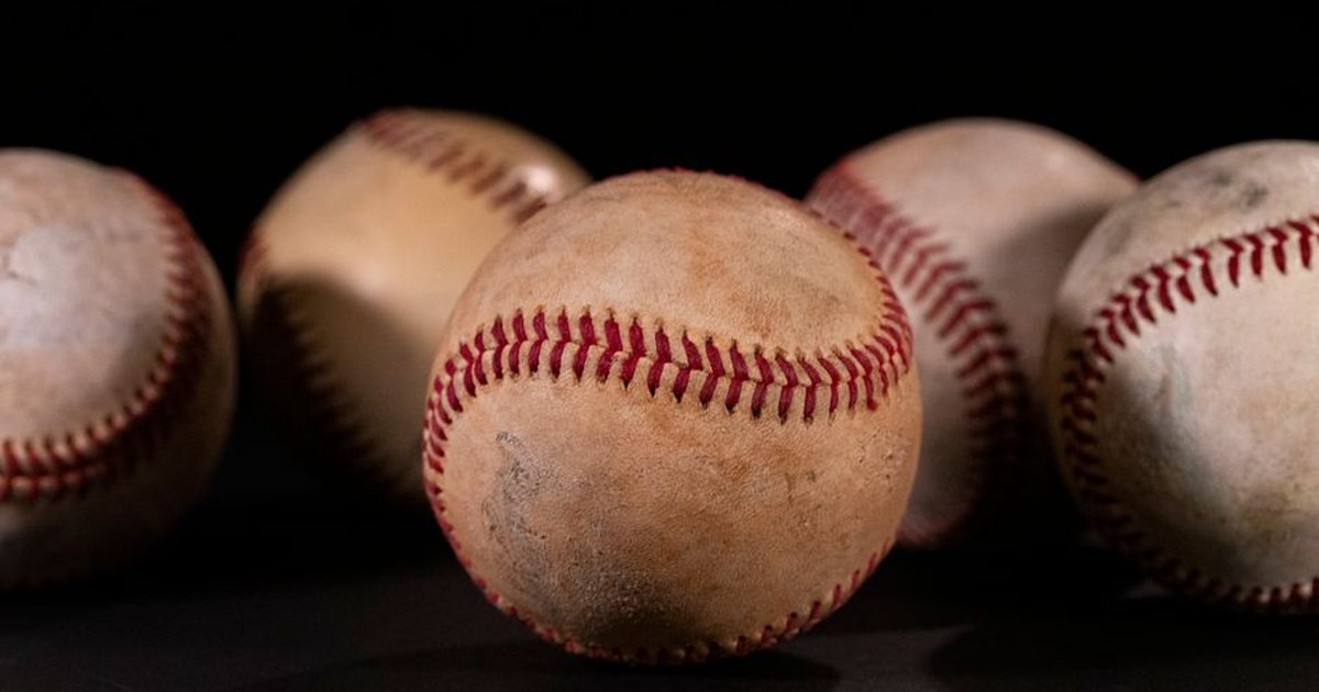 Detailed close-up of vintage baseballs on a dark black background, showcasing texture and stitching.