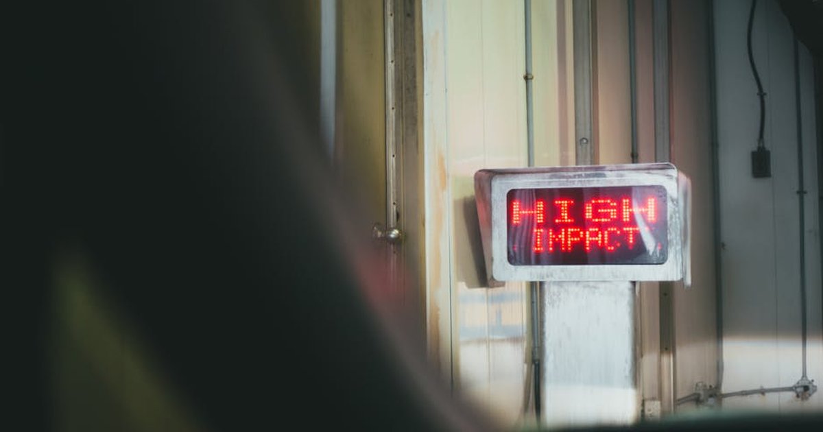 A red LED sign displaying 'HIGH IMPACT' in an indoor setting.