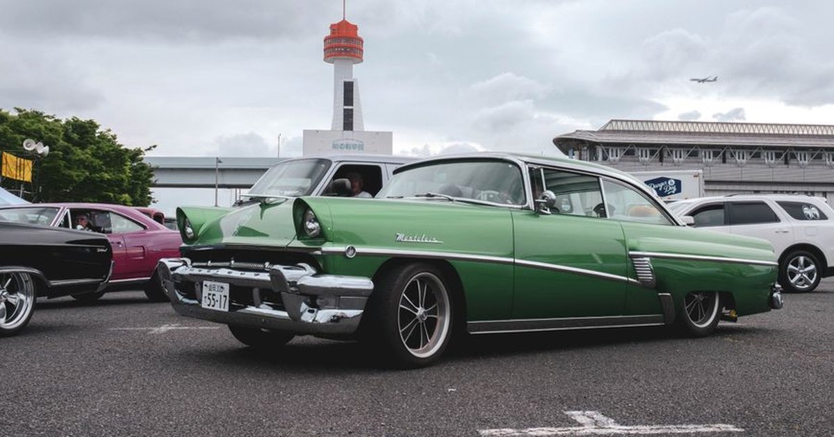 Vintage cars gathered at an urban car meetup, showcasing classic automotive design.