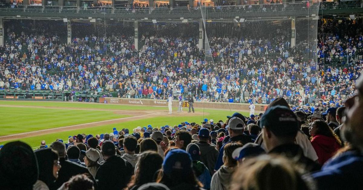Energetic scene of a nighttime baseball game with a packed stadium crowd.