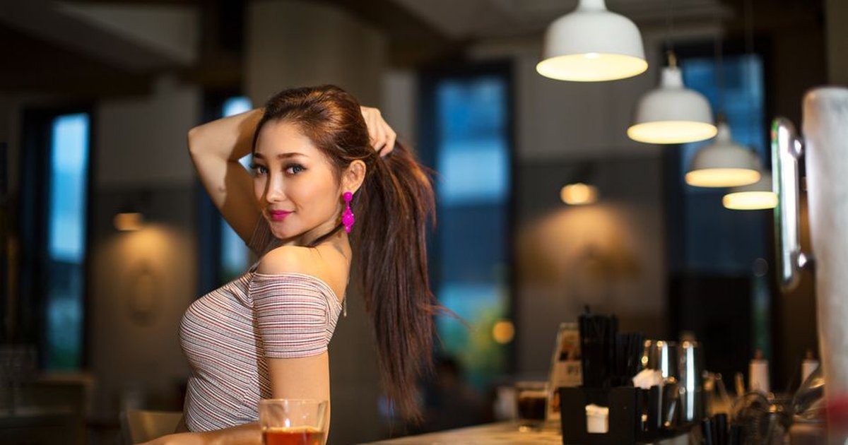 Chic woman posing confidently at a modern bar in North Jakarta, Indonesia.