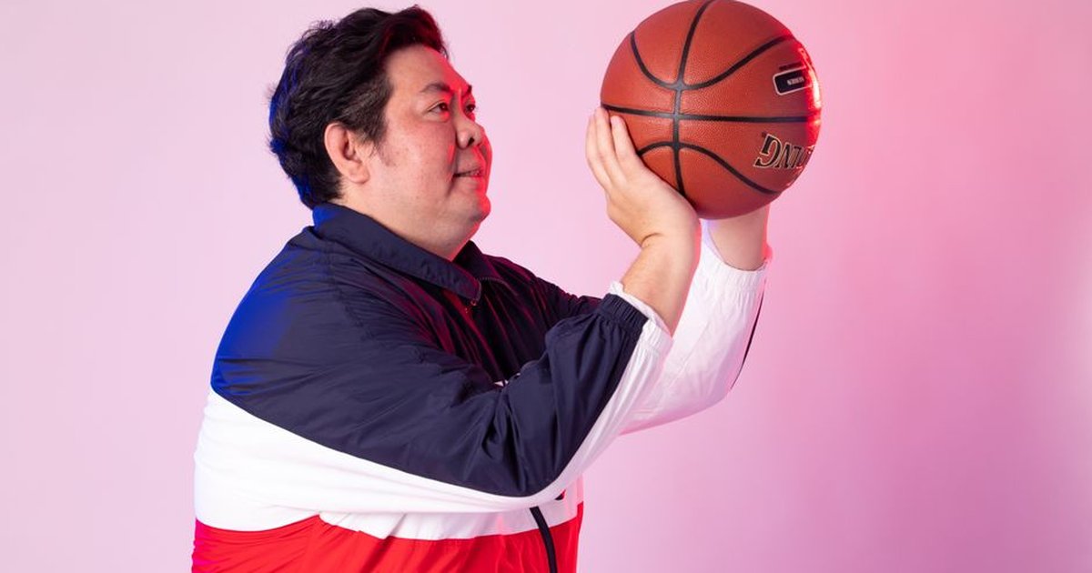 Adult man holding a basketball, preparing to throw in studio.