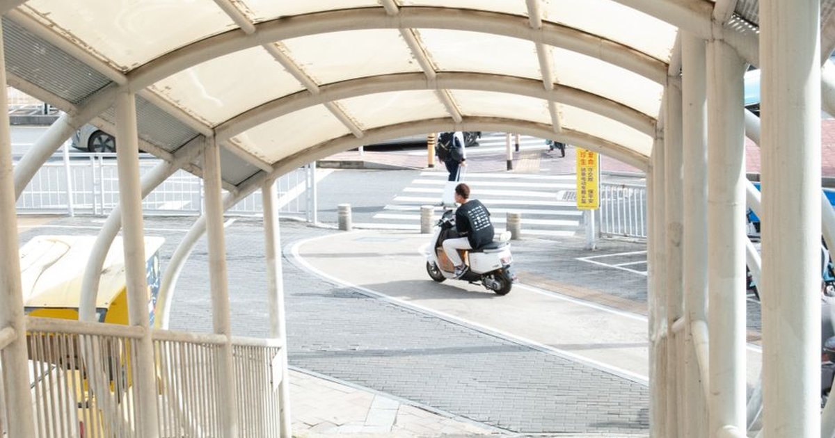 Person riding a scooter through a covered urban walkway, capturing the bustling city atmosphere.